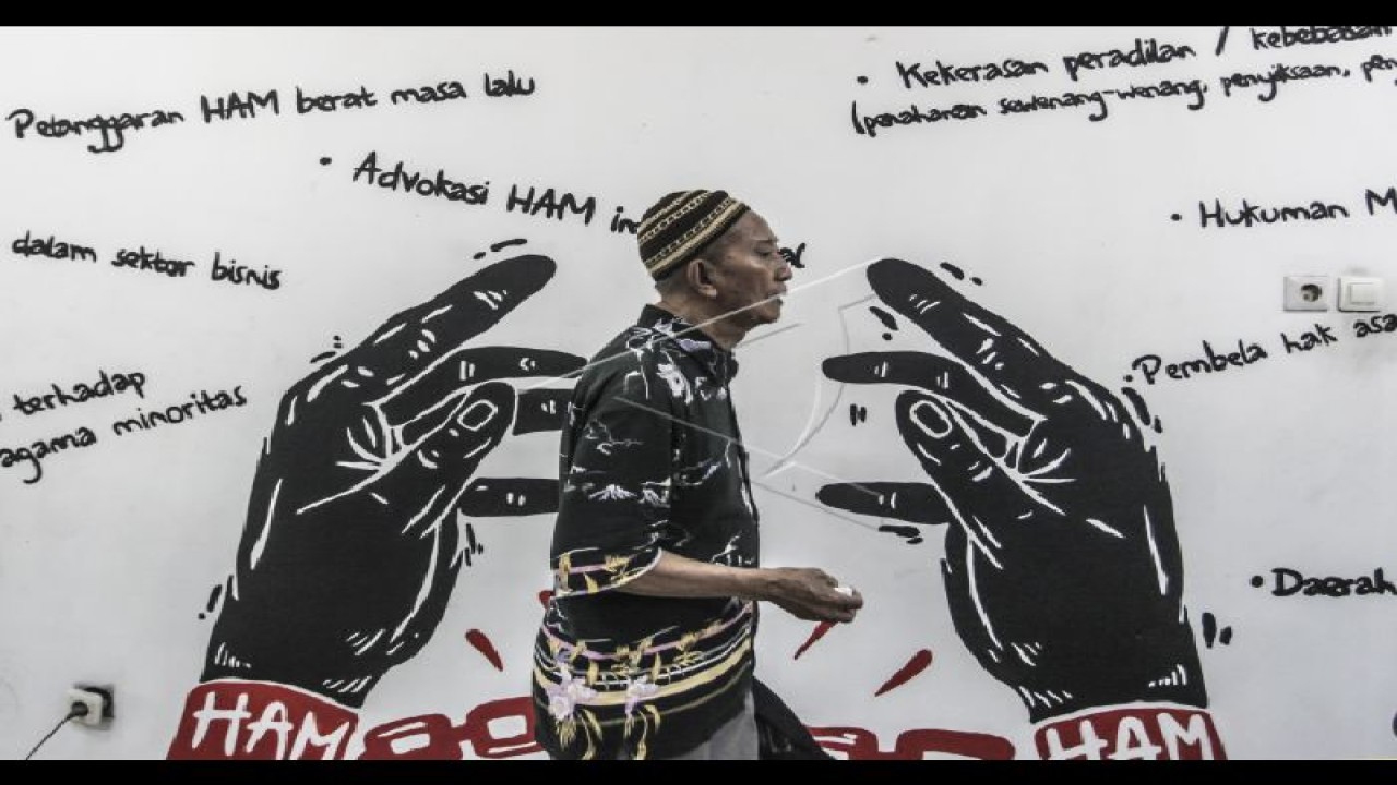 Ilustrasi - Salah satu anggota keluarga korban pelanggaran HAM Berat Masa Lalu melintas di depan mural tentang permasalahan HAM, di kantor Kontras, Jakarta. (ANTARA FOTO/Muhammad Adimaja)