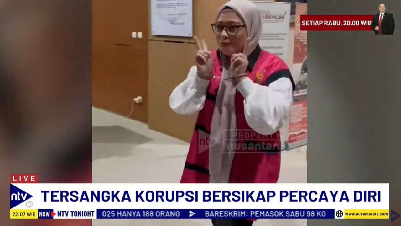 Tersangka korupsi Ari Yuli Ningsih Lindoeno tersenyum dan memberikan salam dua jari.
