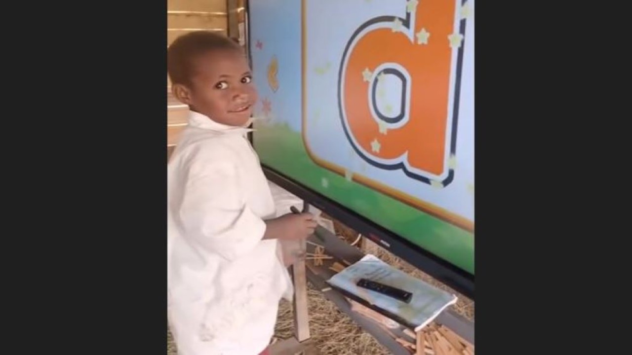 Anak-anak Papua belajar menggunakan papan pintar interaktif.